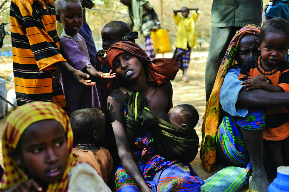 소말리아와 인접한 케냐 다다브 난민캠프에서 소말리아 아이들이 당일 아침에 캠프에 도착해 탈수와 굶주림에 지친 여성에게 비스킷을 전하고 있다. 2011년 8월 20일. 사진 린지 아다리오, 문학동네 제공.Somali children try to feed a woman biscuits as she suffers from dehydration and hunger moments after arriving at a reception center the morning after crossing from Somalia into Kenya, after fleeing a prolonged drought in Somalia, near the Kenyan border with Somalia, at the Dadaab camp August 20, 2011. Dadaab, with roughly 400,000 refugees, Dadaab is the largest refugee camp in the world. The camp is grossly over capacity, and the refugees experience an ever-shrinking access to essential services such as water, sanitation, food and shelter, also because they have been sharing their rations with the new arrivals. At the current pace of arrival MSF estimates that the camp’s population will total 500’000 before the end of 2011, and living conditions are only expected to deteriorate further. Without a long-term solution in sight, Médecins Sans Frontières (MSF) is deeply concerned about the fate of the hundreds of thousands of people who seek refuge in Kenya due to the ongoing conflict in Somalia combined with a looming nutritional crisis after several years of droughThe horn of Africa is suffering one of the worst droughts in years, displacing thousands, and killing others through severe malnutrition.The horn of Africa is suffering one of the worst droughts in years, displacing thousands, and killing others through severe malnutrition. In response to the increasing severity of the situation MSF is operating an emergency nutrition intervention in Turkana.(Credit: Lynsey Addario/ VII Network)