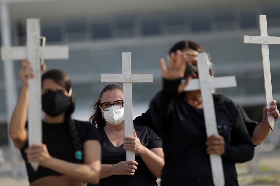 브라질 상원이 코로나19 대응을 게을리한 자이르 보우소나루 대통령을 살인죄 등으로 기소하라는 내용의 보고서를 작성했다. 수도 브라질리아에서 코로나19 사망자들을 추모하는 시위대가 십자가를 들고 있다. 브라질리아/로이터 연합뉴스