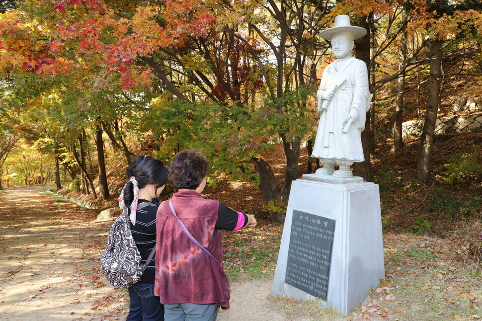 괴산 연풍 새재 과거 길을 찾은 시민들이 선비상 앞에서 새재 과거길 관련 속설을 살피고 있다. 이 길은 수능 대박길로 이름나 전국에서 학부모들이 몰리고 있다.