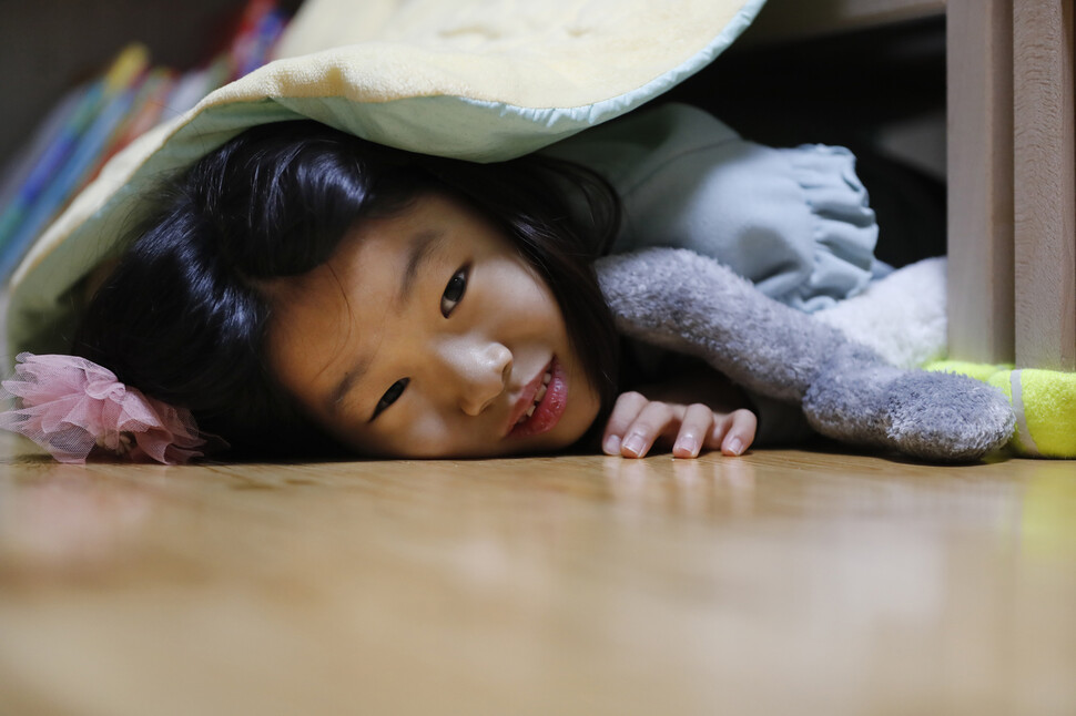 침대 아래 몸을 숨기고 빼꼼 얼굴을 내민 여덟살 은수, ‘취재 거부의 암시인가’ 싶어 사진기자를 긴장시켰습니다.