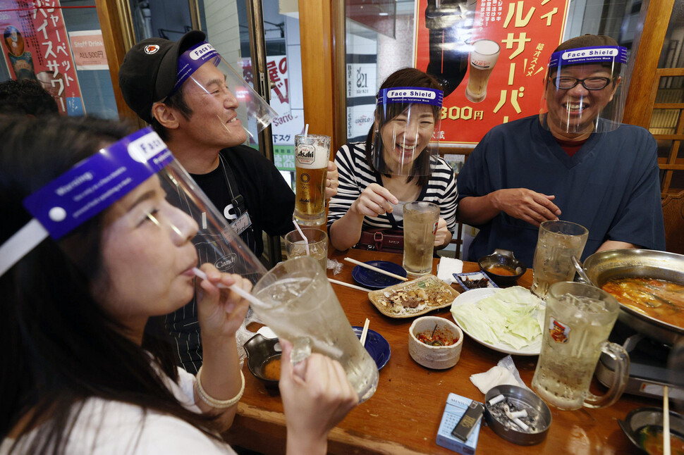 일본 정부가 오사카부, 교토부, 효고현 등 간사이 지역 3개 광역자치단체의 신종 코로나바이러스 감염증(코로나19) 긴급사태를 해제하자 지난 5월 25일 얼굴 보호구를 착용한 시민들이 오사카의 한 펍에 모여 앉아 있다. 오사카 AP/연합뉴스