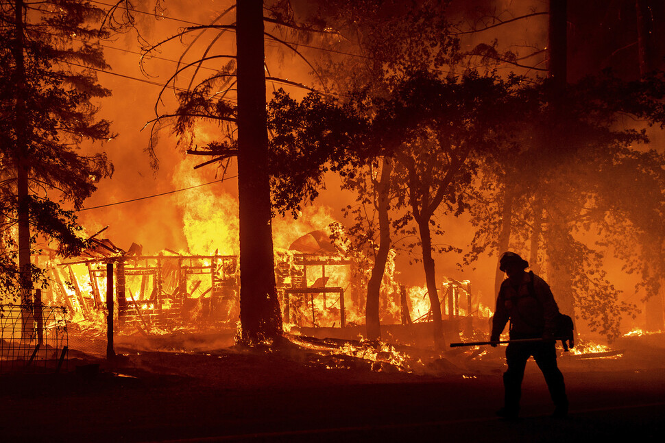 미국 캘리포니아주 플루머스 카운티에서 지난 7월24일(현지시각) ‘딕시’란 이름의 대형 산불이 주택을 불태우고 있는 화재 현장을 한 소방관이 지나고 있다. 미 서부 13개 주에서는 극심한 가뭄에 폭염이 겹치면서 80여건의 산불이 발생해 주변으로 번졌다. 연합뉴스