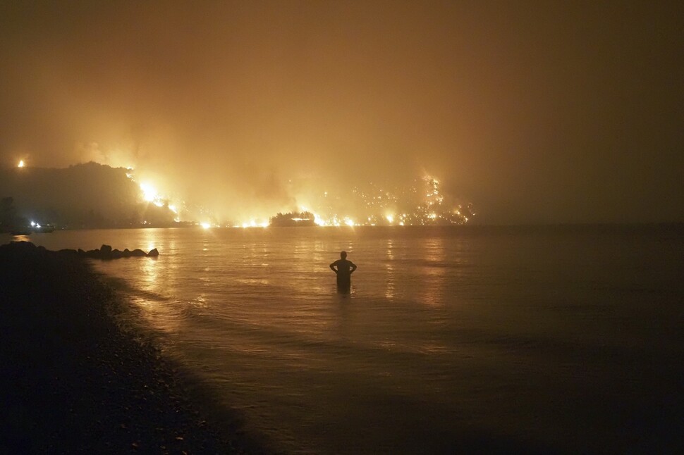지난 8월6일(현지시각) 그리스의 에비아섬 림니 마을의 한 주민이 산불이 해변 쪽으로 번지는 광경을 바라보고 있다. 기록적인 폭염의 영향으로 그리스에서는 7월말부터 곳곳에서 산불이 잇따라 발생했다. 연합뉴스