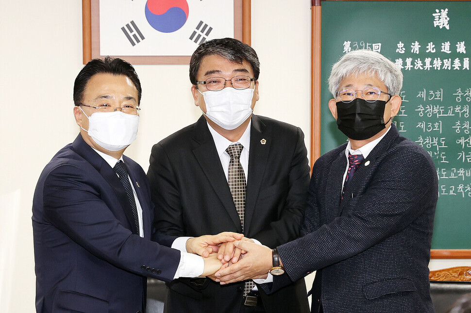 서승우 충북도 행정부지사, 서동학 충북도의회 예산결산위원장, 김성근 충북부교육감(왼쪽부터) 등이 14일 보육재난지원금 지급 등에 합의한 뒤 손을 잡고 있다. 충북도의회 제공