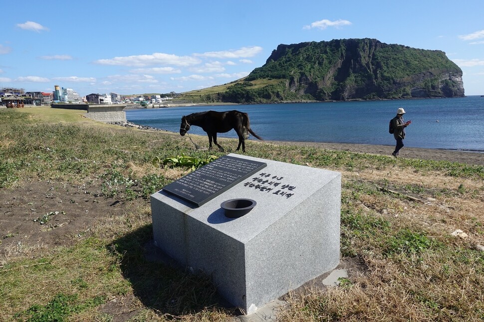 한 도보 여행객이 제주 서귀포시 성산읍 성산일출봉을 배경으로 제주올레 1코스를 걷고 있다.