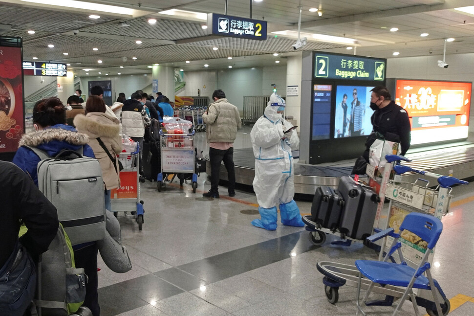 중국 청두 공항 국제선 항공편으로 도착한 승객들이 개인 보호 장비(PPE)를 착용한 직원 옆에서 줄을 서서 기다리고 있다. 로이터 연합뉴스.