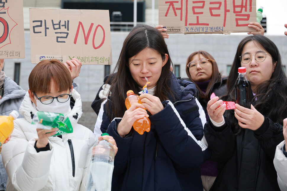 대구환경연합 자원순환프로젝트팀 ‘쓰레기고객센터’와 서울환경연합 활동가들이 29일 오후 서울 종로구 세종문화회관 계단에서 플라스틱 병입음료 제조사와 판매사에 무라벨 정책 도입을 촉구하고 나서 라벨을 뜯는 데에 걸리는 시간을 직접 측정하고 있다. 김혜윤 기자 unique@hani.co.kr