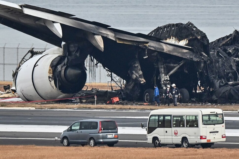 3일 일본 정부 당국자들이 전날 오후 도쿄 하네다 공항에서 해상보안청 항공기와 충돌한 뒤 전소된 일본항공 여객기를 둘러 보고 있다. 도쿄/AFP 연합뉴스