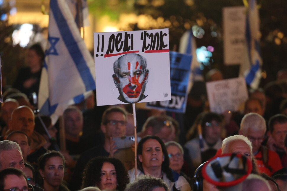 20일(현지시각) 이스라엘 텔아비브의 광장에서 반정부 시위가 열리는 가운데 한 시민이 베냐민 네타냐후 총리의 얼굴이 담기고 히브리어로 “책임”, “유죄”라고 적힌 손팻말을 들고 있다. EPA 연합뉴스