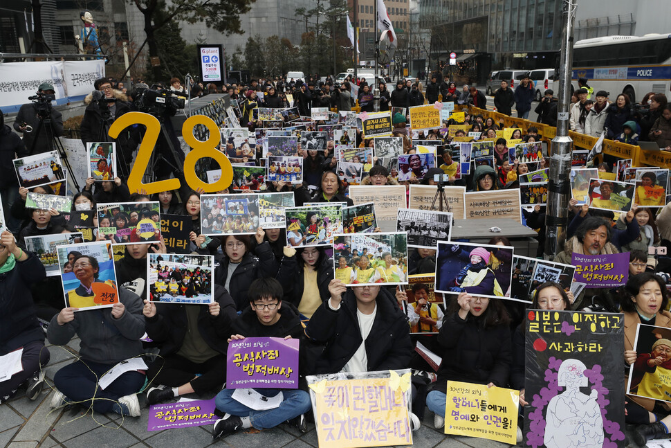 8일 낮 열린 제1421차 수요시위에서 참가자들이그동안 수요시위에 함께 참가한 할머니들의 사진들과 다양한 손팻말을 들어보이며 일본의 공식 사죄를 촉구하고 있다. 이정아 기자