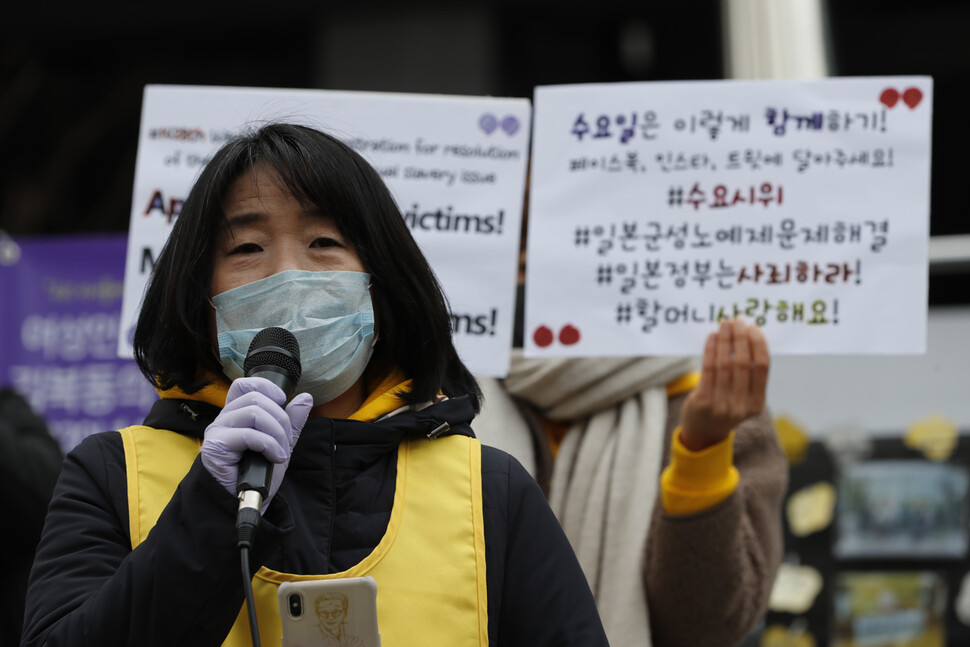 경과보고를 하는 윤미향 정의기억연대 대표 뒤에서 활동가들이 각종 사회관계망서비스를 통해 온라인 수요시위에 참여하는 방법을 안내하는 손팻말을 들고 있다. 이정아 기자 leej@hani.co.kr