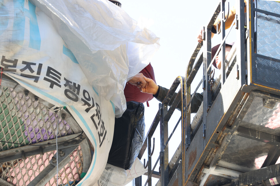 삼성 해고노동자 김용희 씨가 고공농성 300일째인 4일 오후 삼성전자 서초사옥이 있는 서울 강남역 사거리 교통 폐회로텔레비전(CCTV) 철탑 위에서 연대하기 위해 찾아온 방승아 과천 철거민 대책위원회 위원장과 악수하고 있다. 이정아 기자