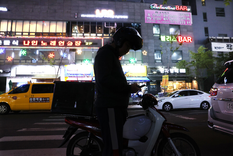 “하루 종일 앉아서 일하니 잠시 쉴 때에는 오히려 서있고 싶어요.” 배달주문을 기다리며 건우 씨가 스마트폰을 확인하고 있다.