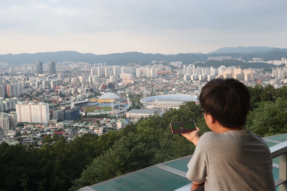 이글스 팬인 나아무개씨가 26일 저녁 대전 보문산 전망대인 보운대(중구)에 올라 경기를 보고 있다. 실제 경기와 손안의 중계에는 몇 초의 간격이 있었다. 대전/백소아 기자