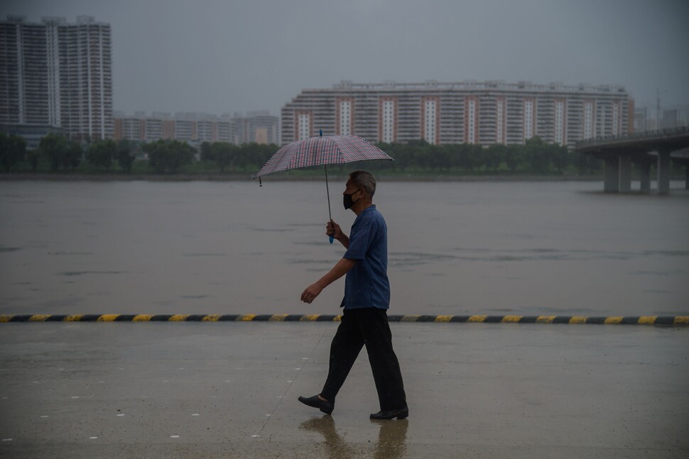 5일 북한 평양에서 우산을 쓴 한 남성이 강물이 불어난 대동강 변을 걷고 있다. 북한에서도 18일째 비 소식이 이어지고 있다. 연합뉴스