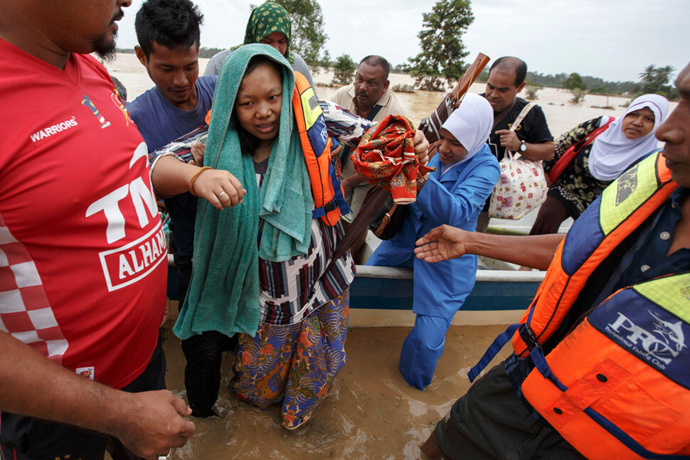 말레이시아에서 한 임신부가 구조대원들 도움으로 홍수로 물에 잠긴 집에서 탈출하고 있다. 카본 브리프 제공