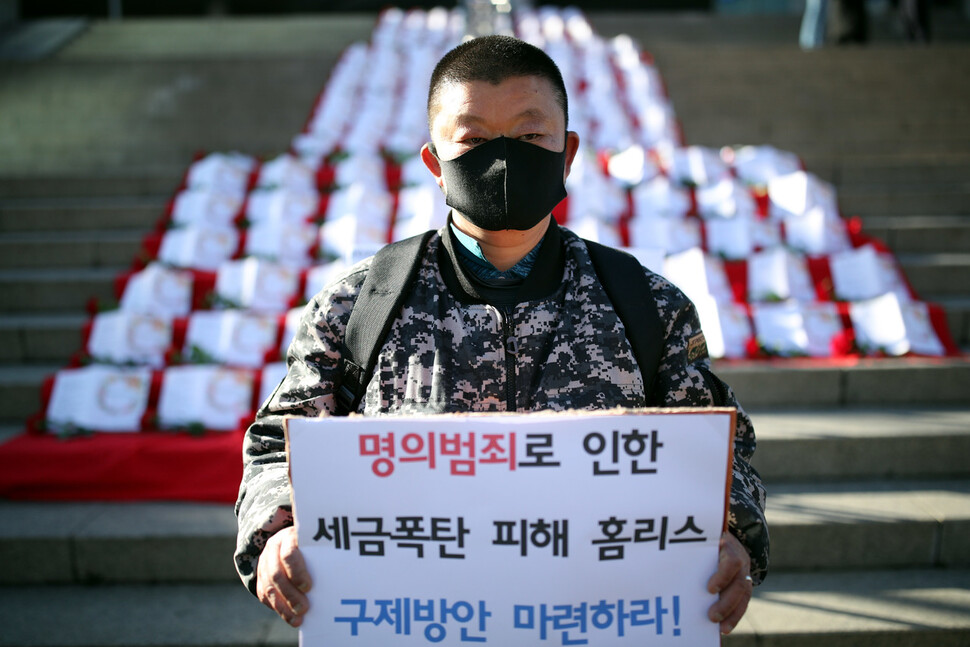 쪽방촌에서 살고있는 ‘아랫마을 홈리스 야학' 학생인 홍난이(46)씨가 ‘명의범죄 홈리스 구제방안 마련하라’란 손팻말을 들고 있다. 김봉규 선임기자