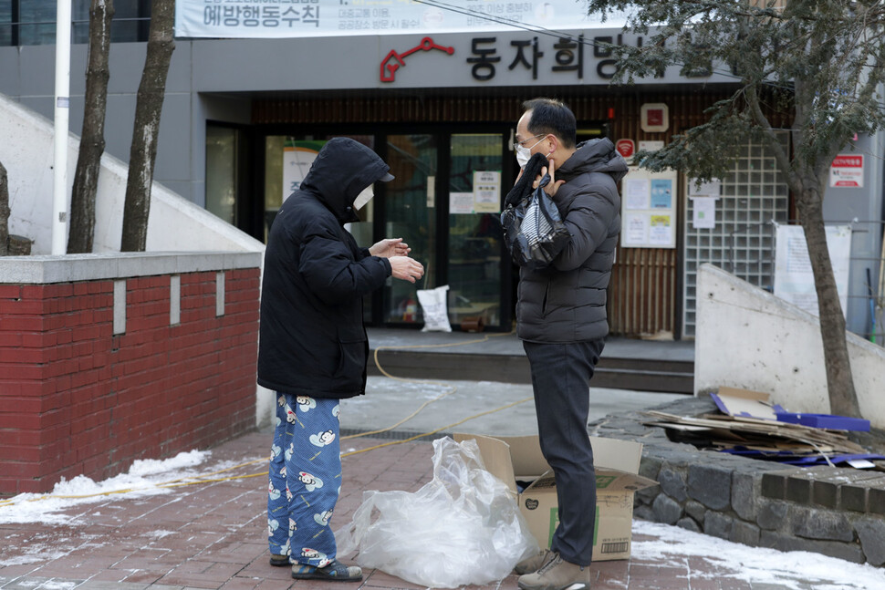 29일 오전 서울 용산구 동자동 새꿈어린이공원에 차려진 `찾아가는 선별진료소'에 코로나19 검사를 받으러 온 쪽방촌 주민에게 김갑록(오른쪽) 서울역 쪽방상담소 소장이 장갑과 목도리를 전해주고 있다. 김혜윤 기자