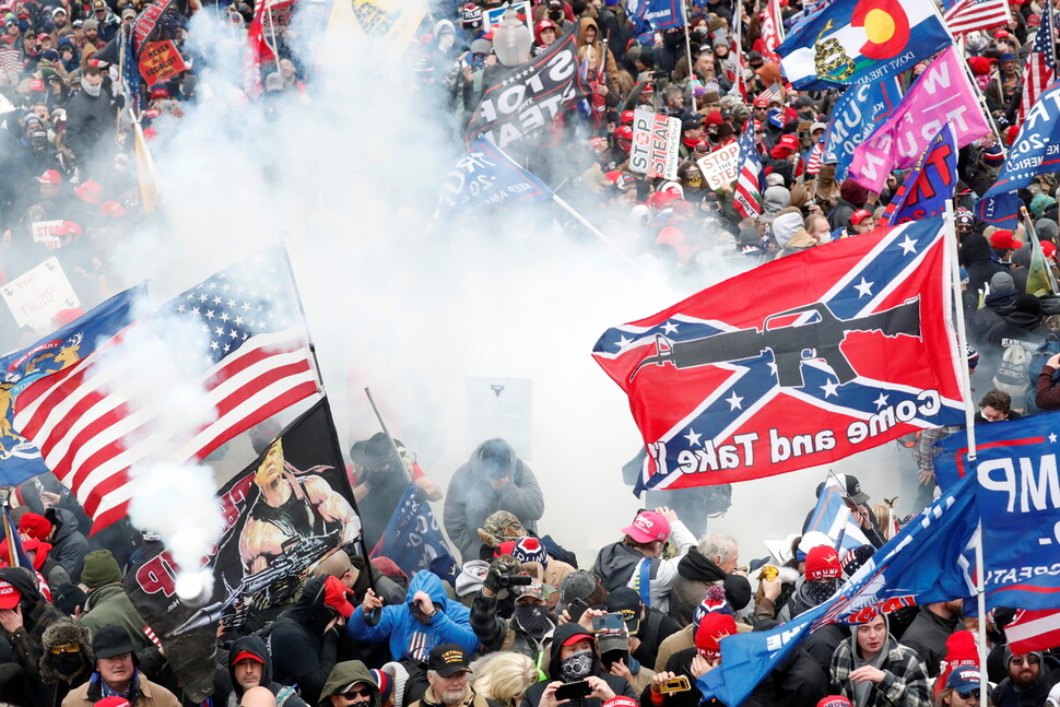 6일 남부연합군 깃발과 성조기를 든 도널드 트럼프 지지자들이 워싱턴 의사당 앞에서 최루탄을 터뜨리는 의회 경찰대와 대치하고 있다. 워싱턴/로이터 연합뉴스