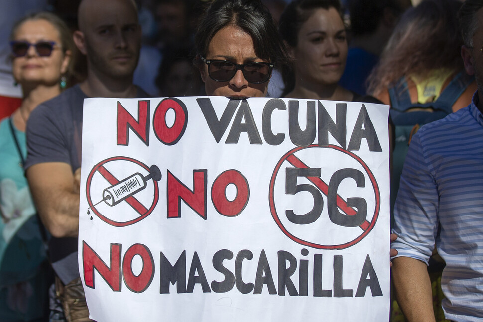 스페인 마드리에서 집회 참가자가 “백신 반대, 5G 반대, 마스크 반대”라는 구호가 적힌 손팻말을 들고 있다. AP 연합뉴스