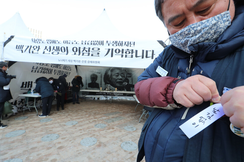 18일 낮 서울광장에 설치된 백기완 통일문제연구소장 시민분향소에서 조문을 마친 한 노동자가 추모 리본을 달고 있다. 강창광 선임기자