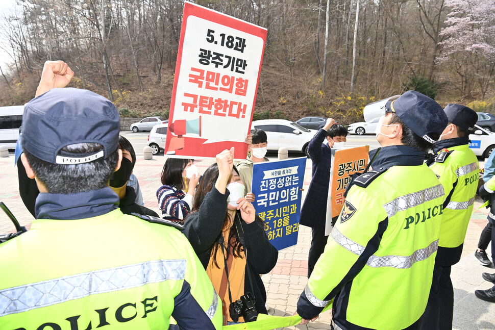 24일 오전 국립 5·18 민주묘지에서 국민의힘 김종인 비상대책위원장의 참배에 대학생들이 피켓을 들고 항의하고 있다. 연합뉴스