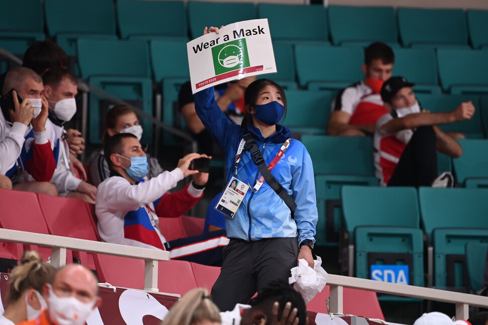 도쿄올림픽 자원봉사자가 28일 일본 도쿄 지오다구 일본 무도관에서 열린 유도 경기에서 마스크를 써달라는 문구의 손팻말을 들고 있다. 도쿄/올림픽사진공동취재단