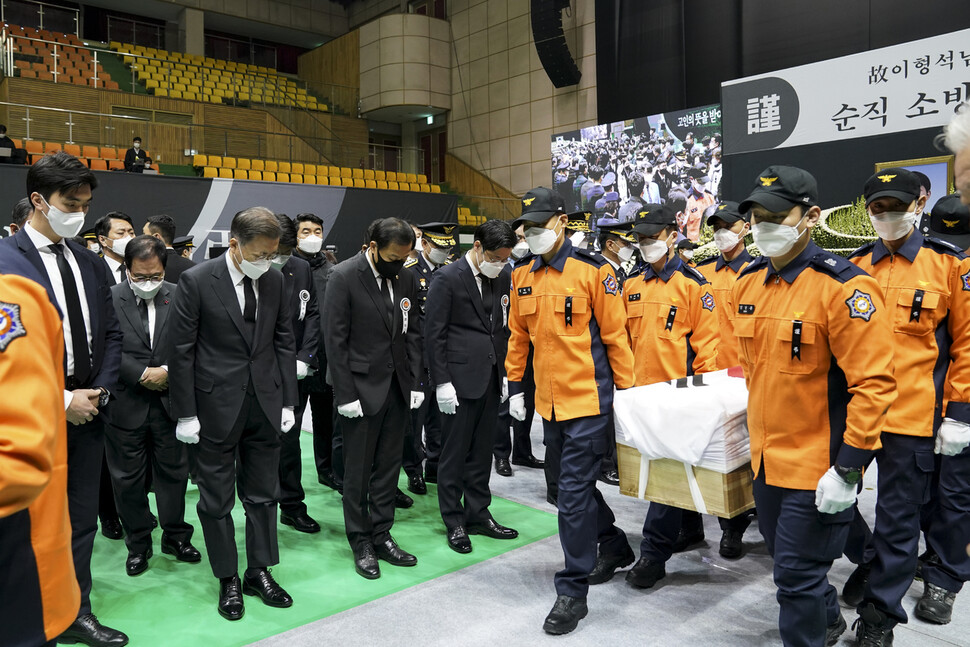 문재인 대통령이 순직 소방공무원들의 운구행렬을 향해 묵념하고 있다. 청와대 제공