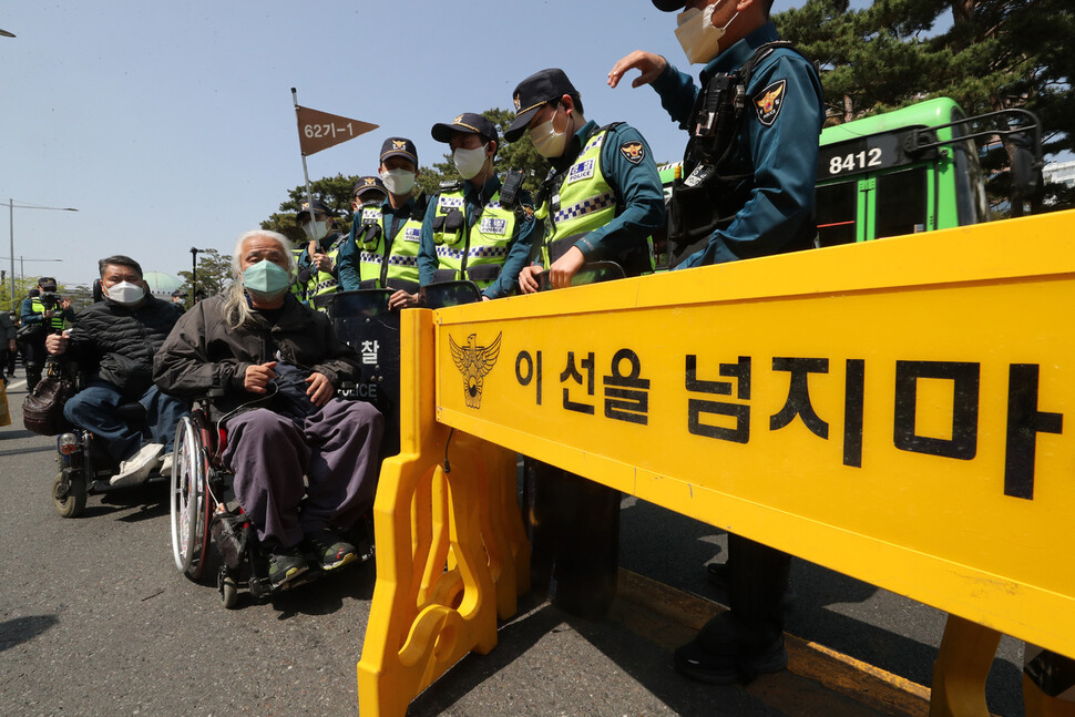 20일 오후 서울 영등포구 여의도 이룸센터 앞에서 ‘420장애인차별철폐투쟁 결의대회’가 열리기 전 경찰이 박경석 전국장애인차별철페연대 대표의 도로 진입을 막고 있다. 김태형 기자