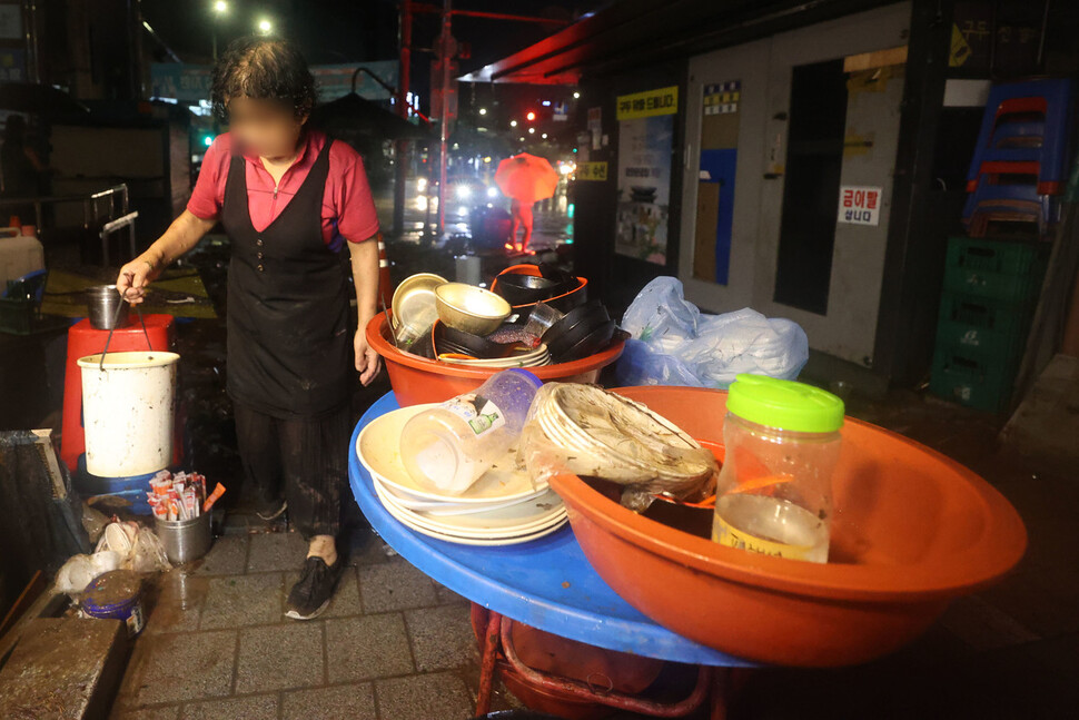 9일 서울 관악구 신대방역에서 포장마차를 운영하는 상인이 폭우로 침수된 포장마차를 정리하고 있다. 연합뉴스