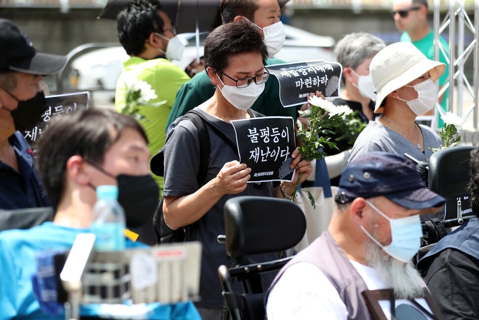 16일 오전 서울 용산 대통령실 앞에서 열린 폭우 희생자 추모주간 선포 기자회견에서 한 참석자가 ‘불평등이 재난이다’가 적힌 손팻말을 들고 있다. 박종식 기자