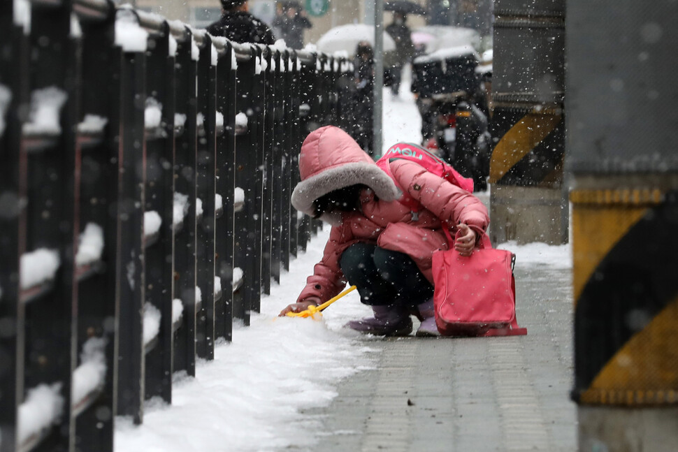 26일 오전 서울 영등포구 영중초등학교 학생이 개학을 맞아 등교하던 중 쌓여있는 눈으로 눈오리를 만들고 있다. 김혜윤 기자