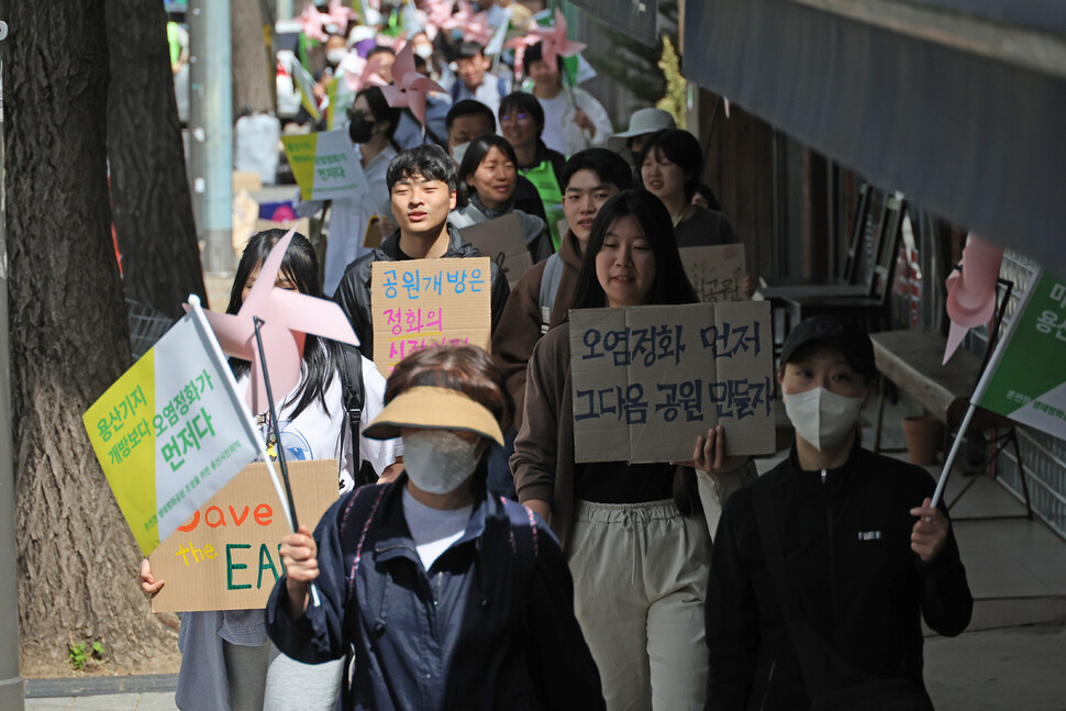 서울환경연합과 온전한 생태평화공원 조성을 위한 용산시민회의 활동가들과 시민들이 손팻말과 깃발, 바람개비 등을 들고 서울 용산구 미군기지 14번 게이트 앞으로 행진하고 있다. 김혜윤 기자