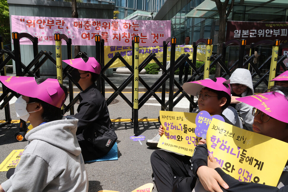 수요시위에 참석한 학생들이 손팻말을 들고 발언을 듣고 있다. 시위현장 인근에 위안부법폐지국민행동, 국민계몽운동본부 등이 만든 펼침막이 걸려있다. 김혜윤 기자