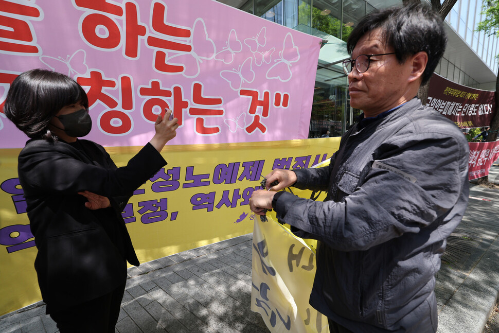 수요시위 현장 인근에서 김병헌 위안부법폐지국민운동 대표(오른쪽)가 정의기억연대 펼침막 위에 펼침막을 걸고 있다. 김혜윤 기자