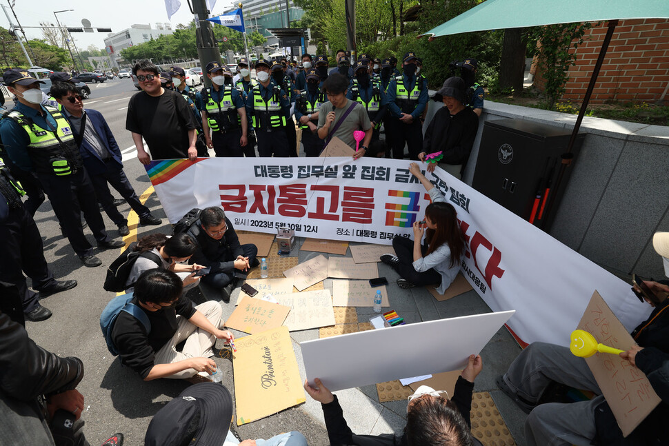 공권력감시 대응팀 회원들이 윤석열 대통령 취임 1주년을 맞아 서울 용산구 대통령실 입구에서 대통령 집무실 앞 집회 금지를 규탄하는 ‘금지통고를 금지한다’는 집회를 하려다 경찰에게 제지당하자 그 자리에 앉아 종이 피켓에 구호를 적고 있다. 윤운식 선임기자 yws@hani.co.kr