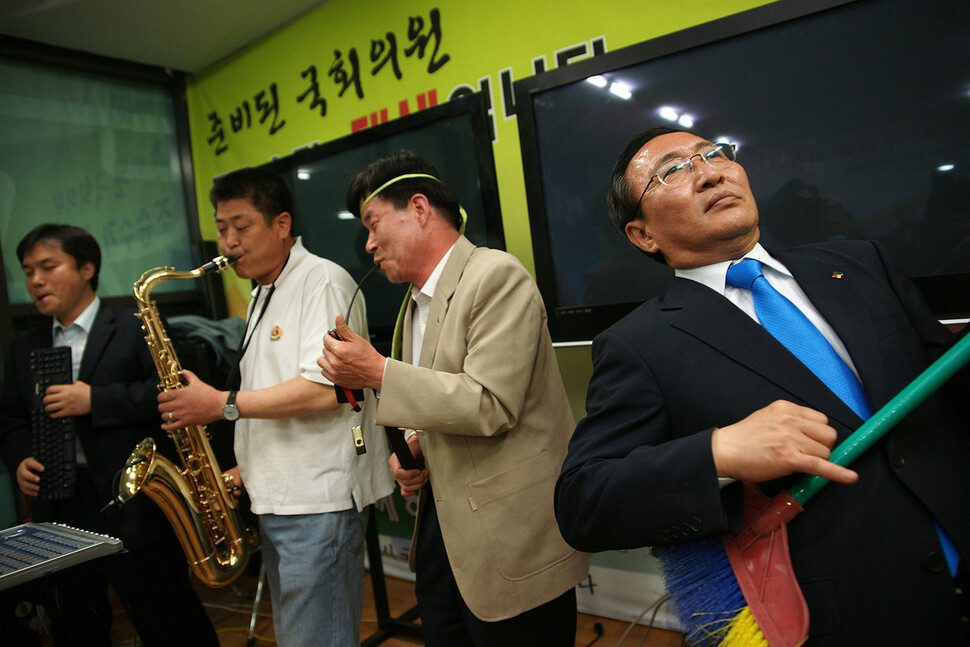 2009년 4월30일 울산 국회의원 보궐선거에서 조승수 의원(진보신당)의 당선을 축하하는 파티에서 빗자루를 들고 기타연주를 흉내내는 노회찬(맨 오른쪽)의 모습. ⓒ이상엽. 평등하고 공정한 나라 노회찬재단. 사회평론아카데미 제공