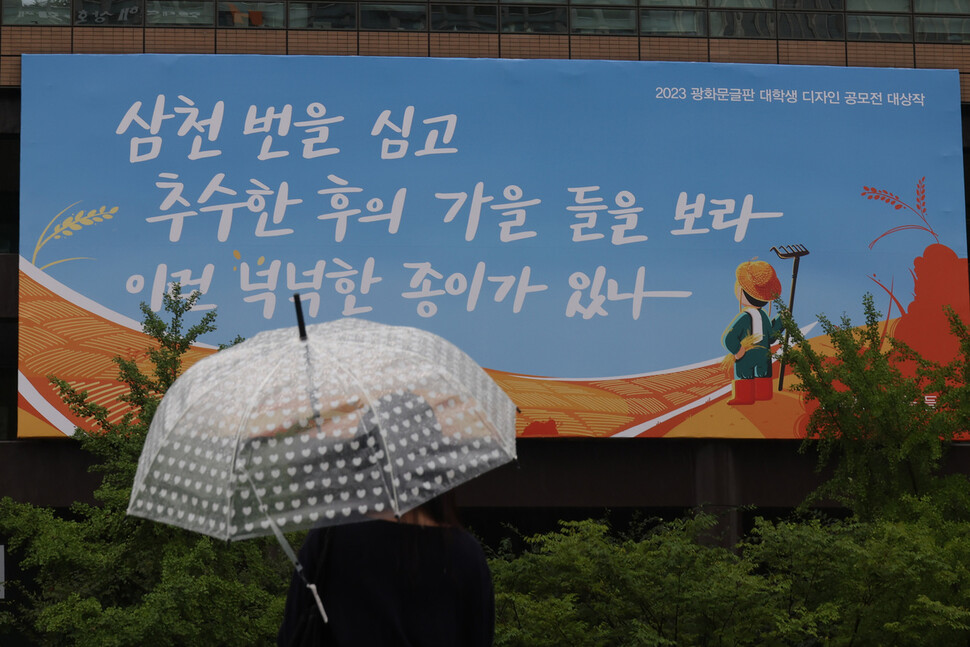 서울 종로구 교보생명 외벽에 걸린 광화문글판 가을편 앞으로 한 시민이 우산을 쓰고 지나가고 있다. 김혜윤 기자