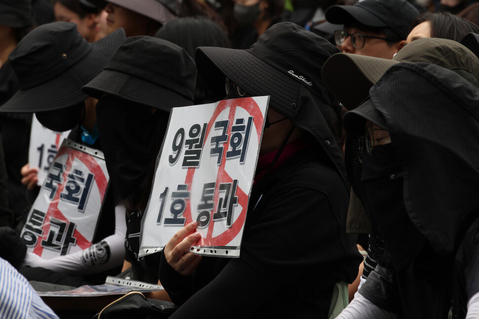 집회 참석자들이 검은 옷을 입고 손팻말을 든 채 현직 초등학교 교사의 발언을 듣고 있다. 김혜윤 기자