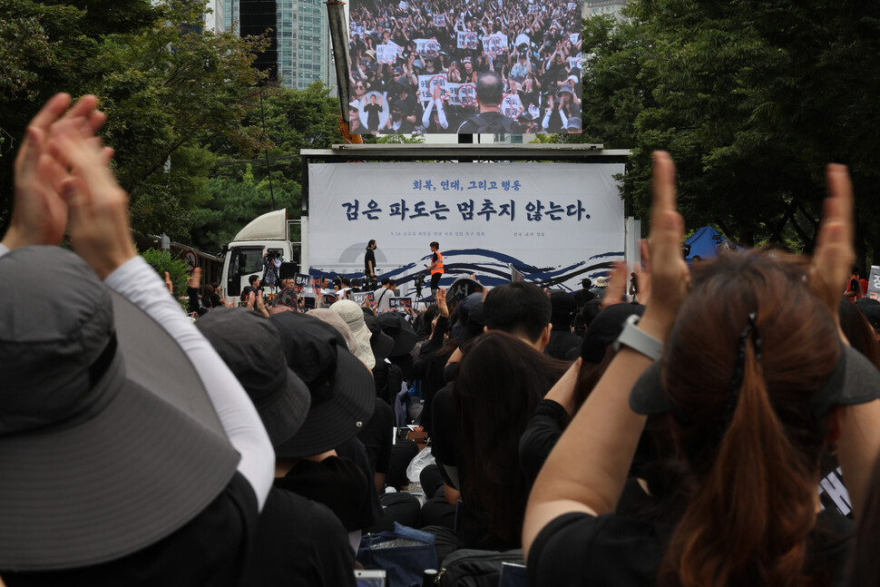 검은 옷을 입은 참석자들이 현직 초등학교 교사의 발언이 끝나자 박수 치고 있다. 김혜윤 기자