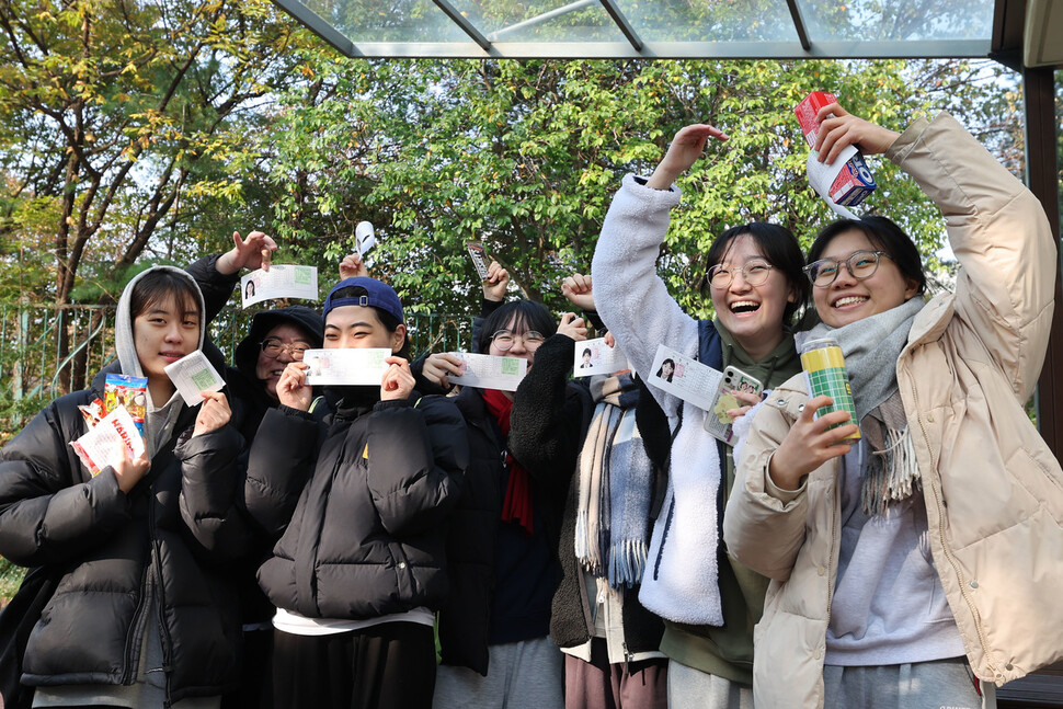 2024학년도 대학수학능력시험을 하루 앞둔 15일 오전 서울 중구 이화여자고등학교에서 3학년 학생들이 취재진을 향해 수험표와 선물을 들어보이며 밝게 웃고 있다. 백소아 기자