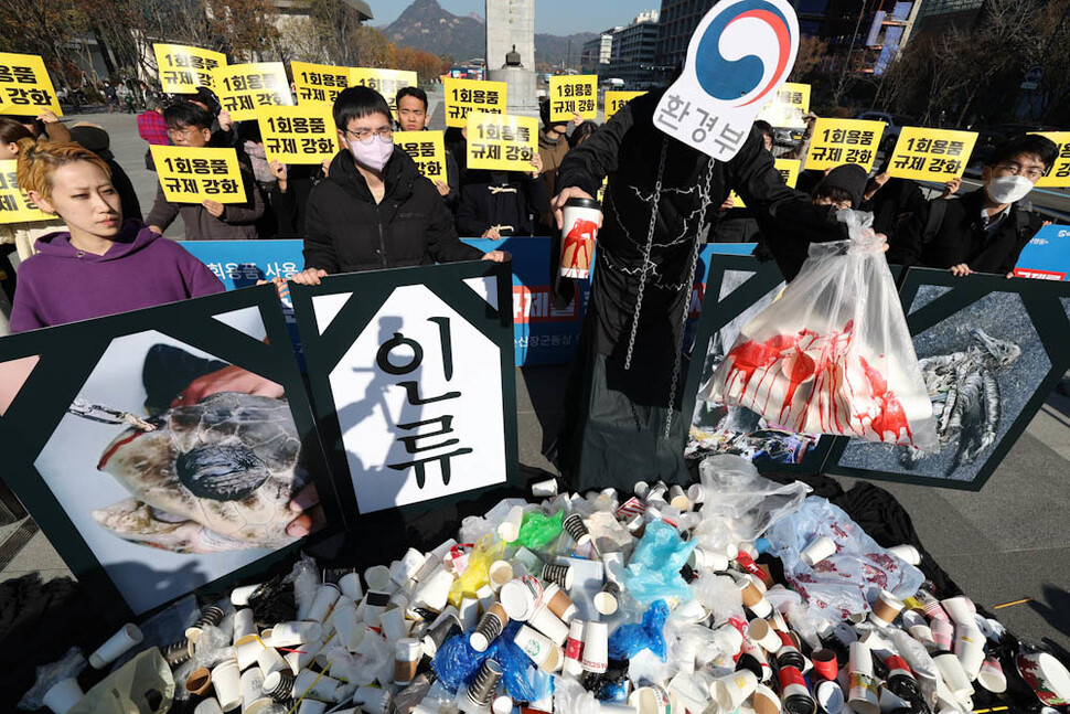 환경운동연합과 녹색연합, 소비자기후행동 등 ‘1회용품 사용 규제 철회 규탄 전국공동행동’ 참여단체 활동가들이 21일 오전 서울 광화문광장에서 환경부가 지난 7일 종이컵과 플라스틱 빨대 등에 관한 1회용품 규제를 철회한 것을 비판하며 환경부가 환경을 파괴하는 1회용품 쓰레기에 둘러싸여 있는 모습을 나타내는 행위극을 하고 있다. 김정효 기자 hyopd@hani.co.kr