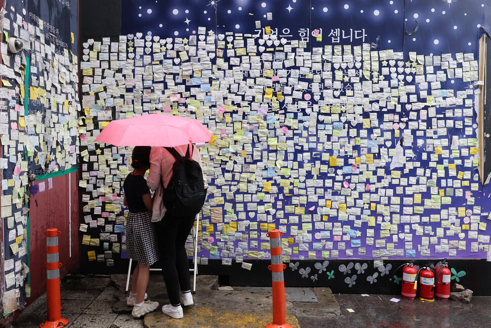 이태원 참사 발생 299일째인 23일 낮 서울 용산구 참사 현장 한 켠에 마련된 추모공간에서 외국인 관광객들이 추모메시지를 적고 있다. 백소아 기자 thanks@hani.co.kr