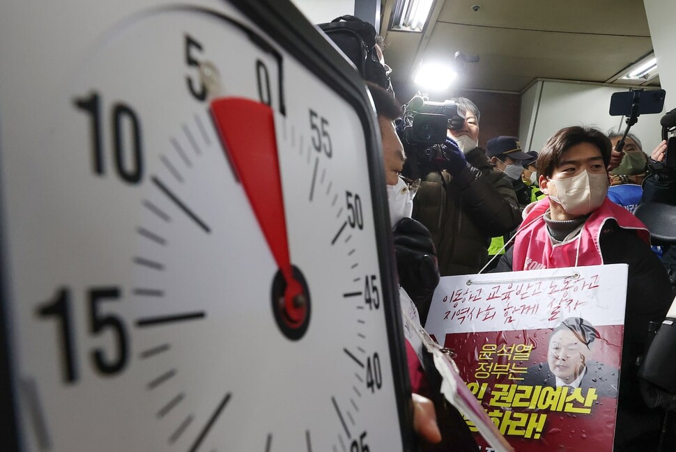 전국장애인차별철폐연대(전장연) 회원들이 2일 오전 서울 지하철 4호선 삼각지역 승강장에서 5분이 표시된 시계를 들고 지하철 탑승을 시도하고 있다. 서울중앙지법은 지난달 19일 서울교통공사가 전장연과 이 단체 박경석 대표 등을 상대로 낸 손해배상 소송을 강제조정하며 전장연이 지하철 승하차 시위로 5분을 초과해 지하철 운행을 지연시키면 1회당 500만원을 공사에 지급하도록 했다. 2023.1.2 연합뉴스