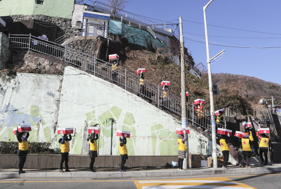 8일 부산 서구 남부민동에서 적십자사 부산지사 봉사자들이 저소득가정에 전달할 구호품을 이고 지고 이동하고 있다. 부산/연합뉴스