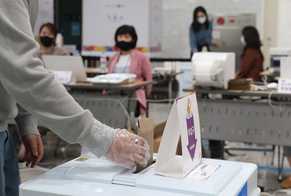 27일 오후 서울 용산구 용산구의회에 마련된 사전투표소에서 한 유권자가 투표용지 봉투를 투표함에 넣고 있다. 신소영 기자