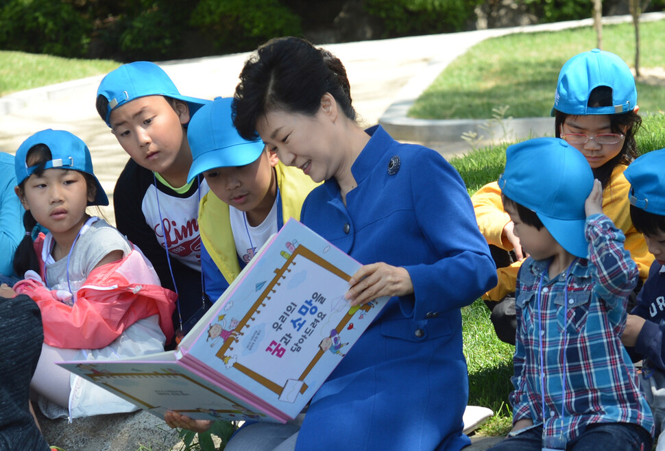 박근혜 대통령이 청와대 녹지원에서 열린 2015년 제93회 어린이날 청와대 초청 행사에서 밝은 표정으로 어린이들에게 책을 읽어주고 있다. 청와대사진기자단