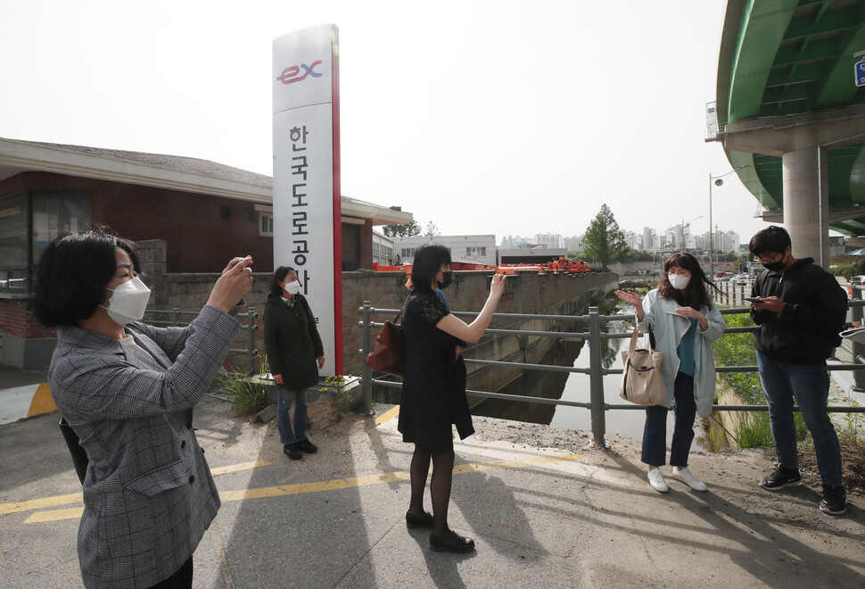 톨게이트 요금 수납노동자들이 14일 경기도 용인시 한국도로공사 수원지사 앞에서 복직 첫 출근을 하기 취재진과 인터뷰를 하는 동료의 모습을 찍고 있다. 백소아 기자