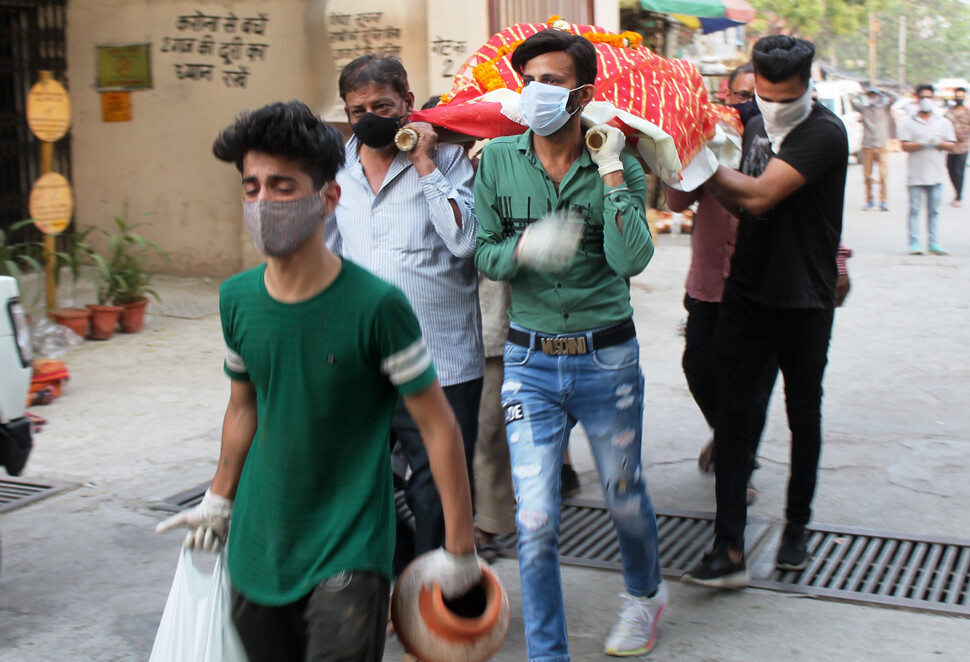 4월 28일 인도 뉴델리에서 코로나19로 숨진 환자의 주검을 사람들이 화장터로 옮기고 있다. 타스/연합뉴스