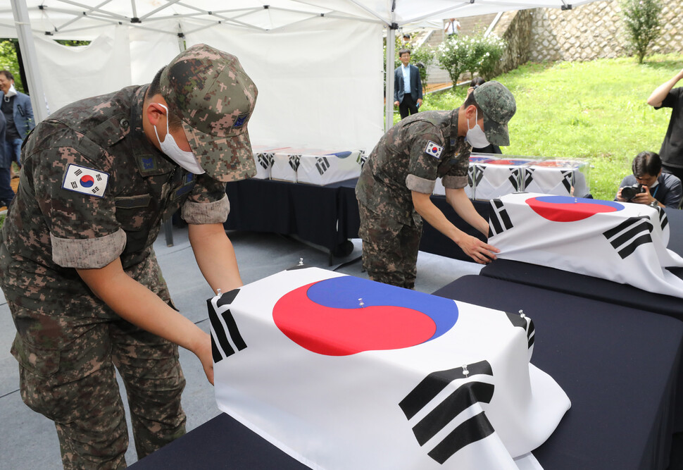 11일 서울 강북구 수유리 광복군 합동묘소에서 열린 ‘수유리 광복군 선열 17위 합동 이장’ 행사에서 국방부 의장대대 장병들이 관을 태극기로 싸고 있다. 공동취재사진